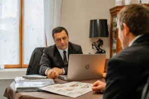 Conseiller funéraire en costume présentant des prestations sur un ordinateur.