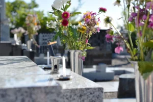 Bouquets de fleurs colorées et bougies sur une tombe en marbre au cimetière.